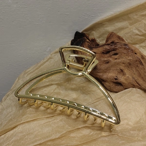 Detailed view of large gold alloy claw clip with polished mirror finish and spring mechanism