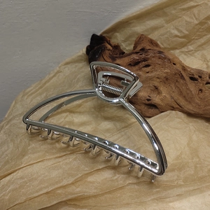 Detail of large silver metal hair claw with polished finish and strong spring clip