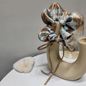 Close-up of elegant blue and brown floral satin scrunchie with long ribbon streamers