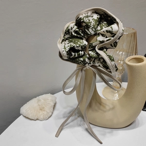 Detail of French style green marble pattern hair scrunchie with beige bow on ceramic vase