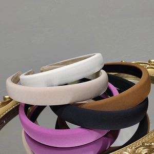 Close-up of padded sponge headbands in five colors on a vintage mirror surface