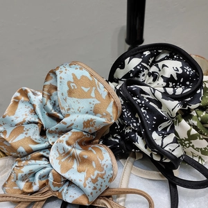 Close-up of silk floral print scrunchies with streamers and detailed edge stitching