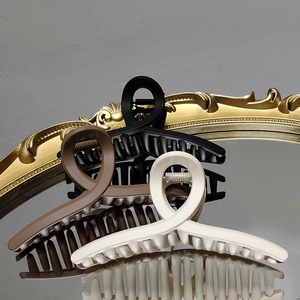 Trois pinces à cheveux mates en noir, marron et crème sur un miroir vintage