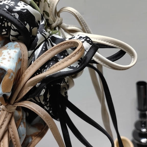 Detailed close-up showing texture of printed silk scrunchies with floral ribbon pattern