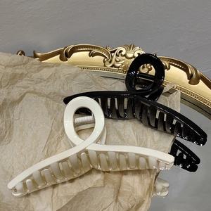 Détail de grandes pinces à cheveux noires et beiges sur un fond de style vintage