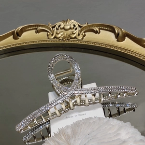 Détail macro d'une pince à cheveux argentée avec strass brillants et ressort doré