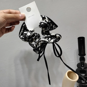 Detail of Korean style floral scrunchie with long black ribbon and brand hangtag