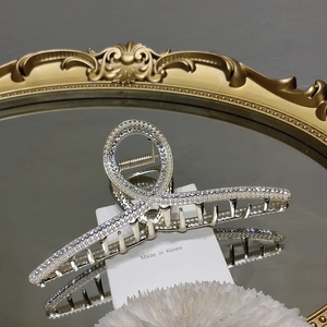 Détail d'une pince à cheveux en alliage argenté avec perles et strass sur plateau miroir