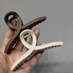 Gros plan de pinces à cheveux mates marron et beige avec design croisé élégant et ressort métal
