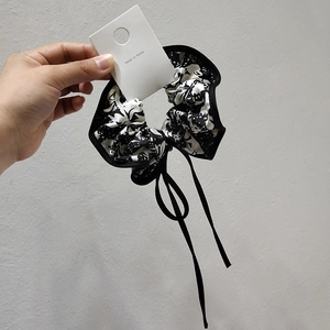Detail of Korean scrunchie with black and white abstract print and long satin ribbon