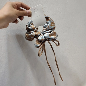Close-up of floral scrunchie with blue fabric and long brown ribbons Made in Korea