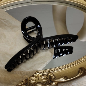Vue détaillée d'une pince à cheveux noire brillante sur un miroir doré vintage