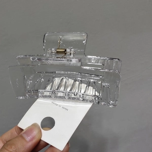 Detail view of transparent rectangular hair claw clip with golden metal spring for women