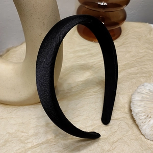 Detail eines dicken schwarzen gepolsterten Stirnbands mit Twill-Satin-Textur auf warmem Grund