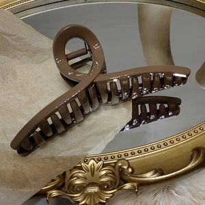 Gros plan d'une grande pince à cheveux marron au design croisé sur un plateau vintage