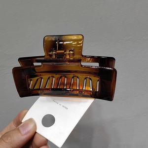 Detail of amber resin hair claw clip with golden metal spring and hollow rectangle design