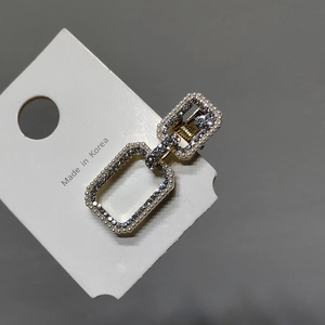 Détail d'une pince à cheveux dorée avec perles et strass sur carte support