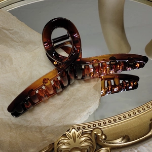 Vue détaillée d'une pince à cheveux ambre translucide avec ressort sur un miroir vintage