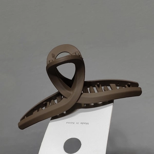 Détail de la pince à cheveux mate marron foncé avec design croisé et étiquette Corée