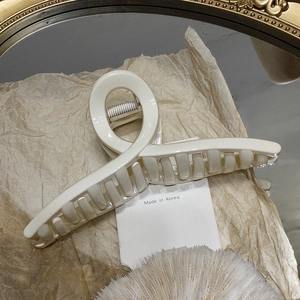 Vue détaillée d'une grande pince à cheveux crème sur papier et miroir doré élégant