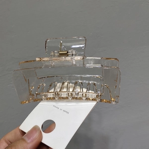 Close-up of amber rectangular claw clip with metal spring on a Made in Korea card