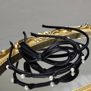 Elegant black satin headband set featuring delicate bows and pearls on a vintage mirror