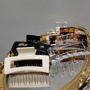Detailed close-up of hollow rectangular hair claws in various colors on a gold vintage tray