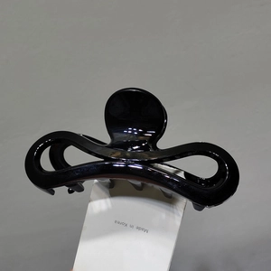 Vue détaillée de la grande pince à cheveux noire brillante avec un design épuré et ressort