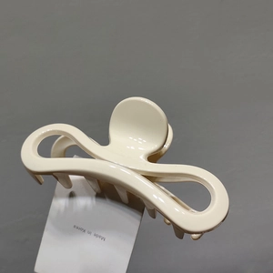 Vue détaillée d'une pince à cheveux crème au design élégant incurvé avec étiquette d'origine