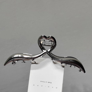Elegant silver metal hair claw clip with hollow heart design on a white display card