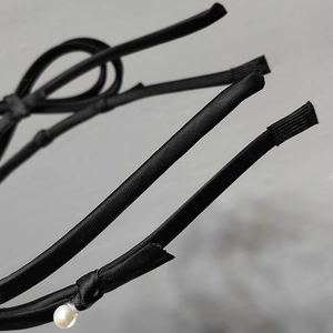 Close-up of black satin headband featuring a multi-strand design with elegant white pearl detail