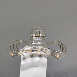 Détail d'une élégante pince à cheveux papillon transparente avec perles dorées