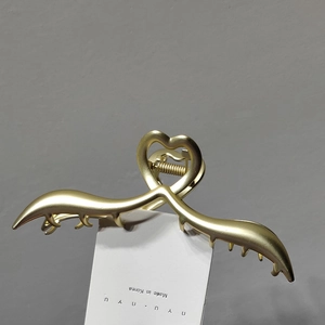 Close-up of matte gold metal heart shark hair claw clip showing spring mechanism