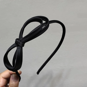 Detailed view of elegant black satin headband with a double-layered bow accessory