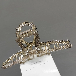 Elegant gold-plated hair claw clip with faux pearls on deep gray background