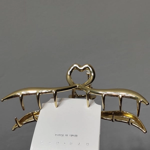 Detailed close-up of a golden heart-shaped metal claw clip with a secure tooth design