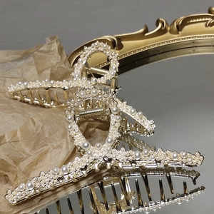Close-up of golden hair claw clip with pearls reflecting on a vintage mirror surface