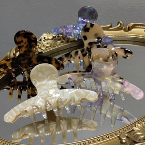 Macro shot of assorted tortoiseshell and marble acetate hair claws on a vintage mirror