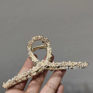 Macro detail of golden alloy hair claw clip featuring intricate pearl inlay craftsmanship