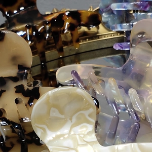 Elegant acetate hair claw clips set with tortoiseshell and marble patterns shown on mirror