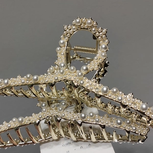 Close-up of golden claw clip with white pearls and durable metal spring mechanism