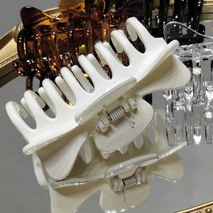 Three elegant cat-ear style hair claws in cream, tortoiseshell and black on a mirror tray