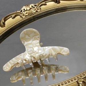 Elegant cream marble pattern acetate hair claw clip on vintage gold mirror display