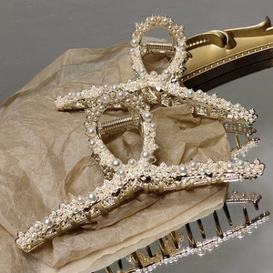 Elegant gold metal hair claw clip with faux pearls in a crisscross design for women