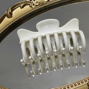 Elegant white glossy hair claw clip for women displayed on a vintage gold mirror