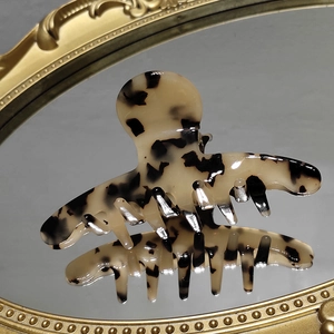 Elegant tortoise shell acetate shark hair claw clip on a vintage mirror surface