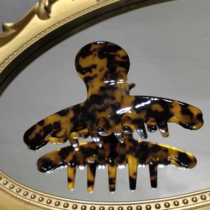 Detail view of tortoiseshell acetate hair claw clip reflecting on a gold-framed mirror