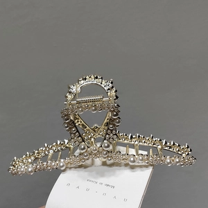 Detail view of large gold hair claw clip with elegant pearls and sparkling rhinestones
