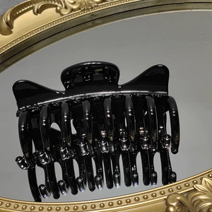 Detailed mirror view of large glossy black cat ear hair claw clip with strong teeth