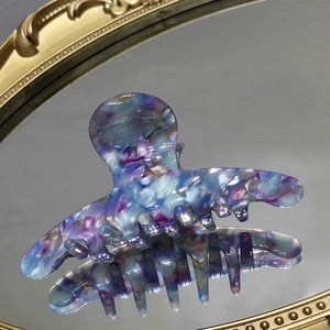 Macro detail of blue marble acetate hair claw clip on vintage gold mirror surface